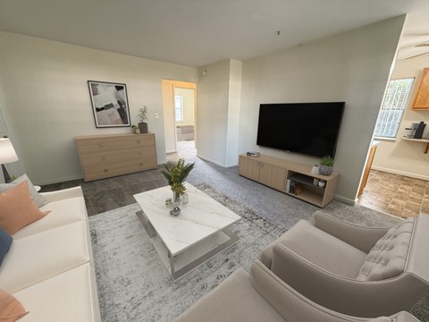 A living room with a grey carpet and a white coffee table.