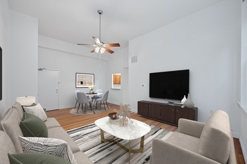 A living room with a grey couch, a coffee table, a television, and a dining table.