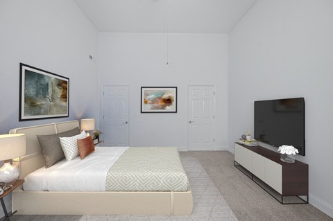 A bedroom with a bed, a nightstand with a lamp, a television, and two framed pictures on the wall.