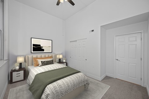 A bedroom with a bed, a ceiling fan, and a painting on the wall.