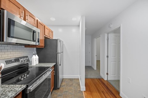 A kitchen with a black refrigerator and stove top oven.