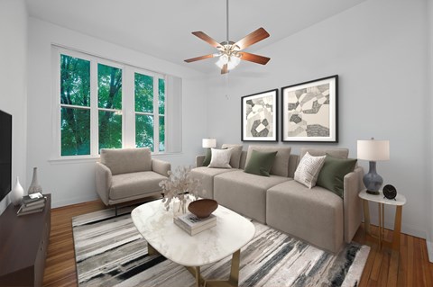 A living room with a beige couch, a white coffee table, and a ceiling fan.