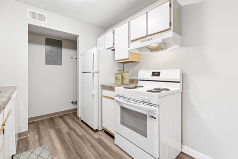 A white kitchen with a refrigerator, oven, and cabinets.