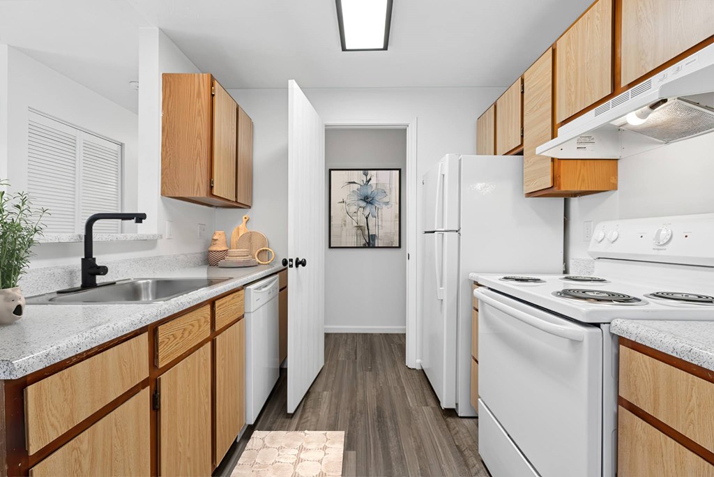 A kitchen with white appliances and wooden cabinets.