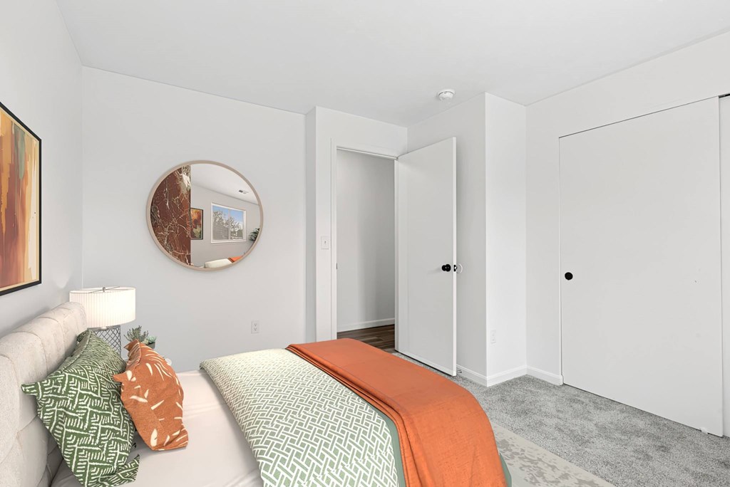 A bedroom with a bed, a couch, and a painting on the wall.