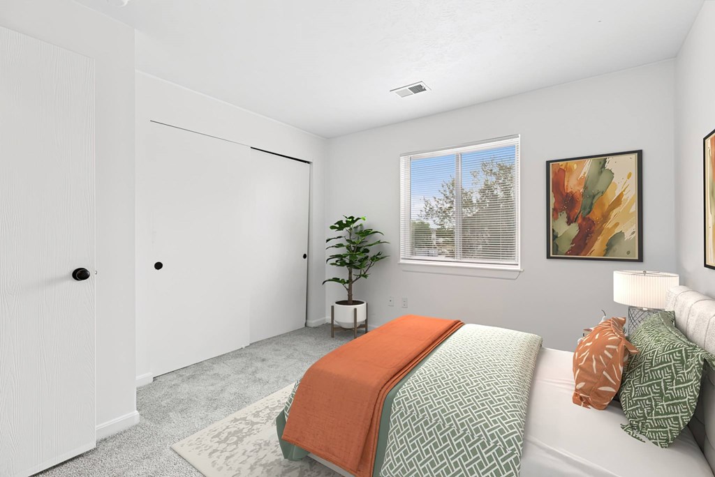 A bedroom with a bed, pillows, and a window.