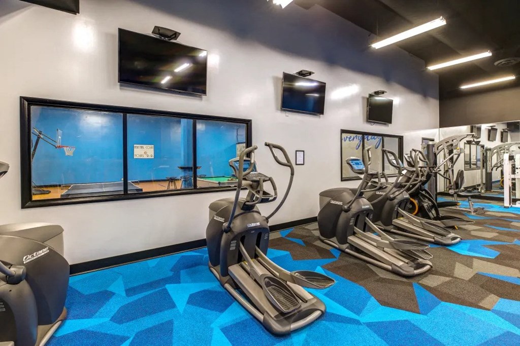 a gym with cardio machines and televisions in a building