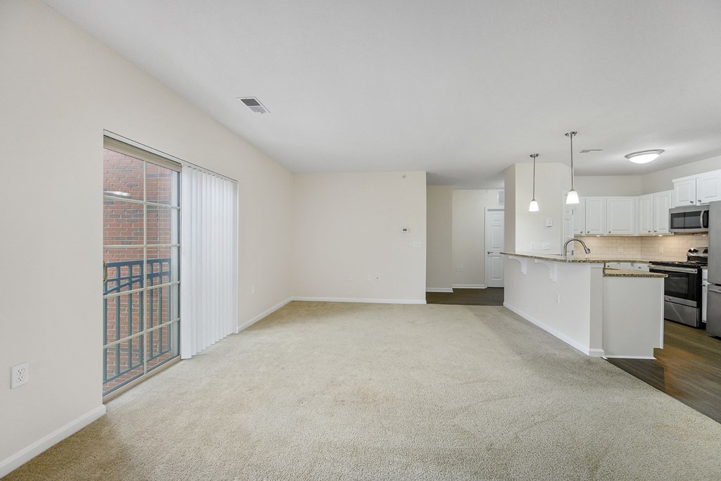 an empty living room and kitchen with a door to a balcony