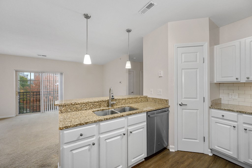 an empty kitchen with white cabinets and a granite counter top