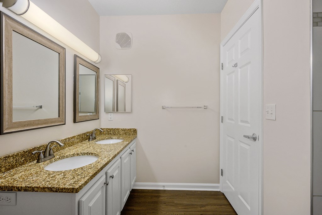 a bathroom with two sinks and two mirrors and a shower
