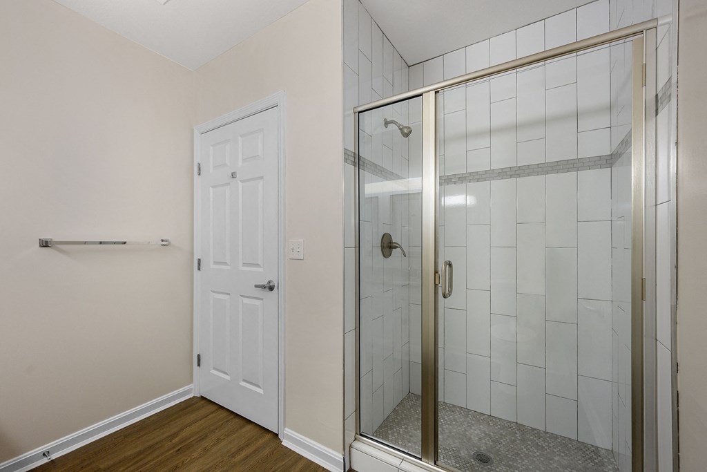 a bathroom with a glass shower door and a door to the closet