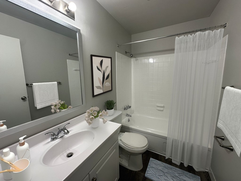 A bathroom with a white sink, toilet, and shower curtain.