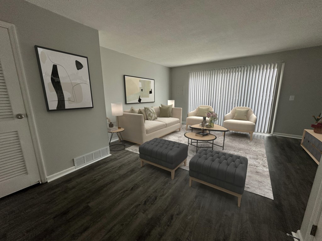 A living room with a grey couch, a black ottoman, and a painting on the wall.