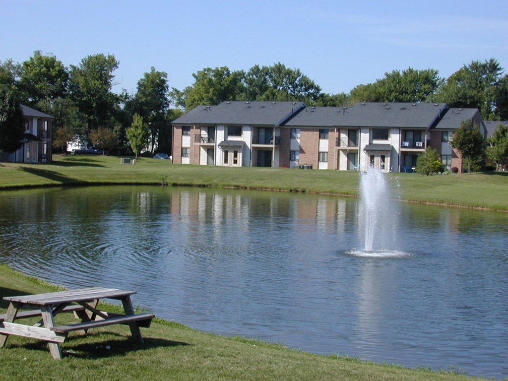 a pond with a fountain in front of a building