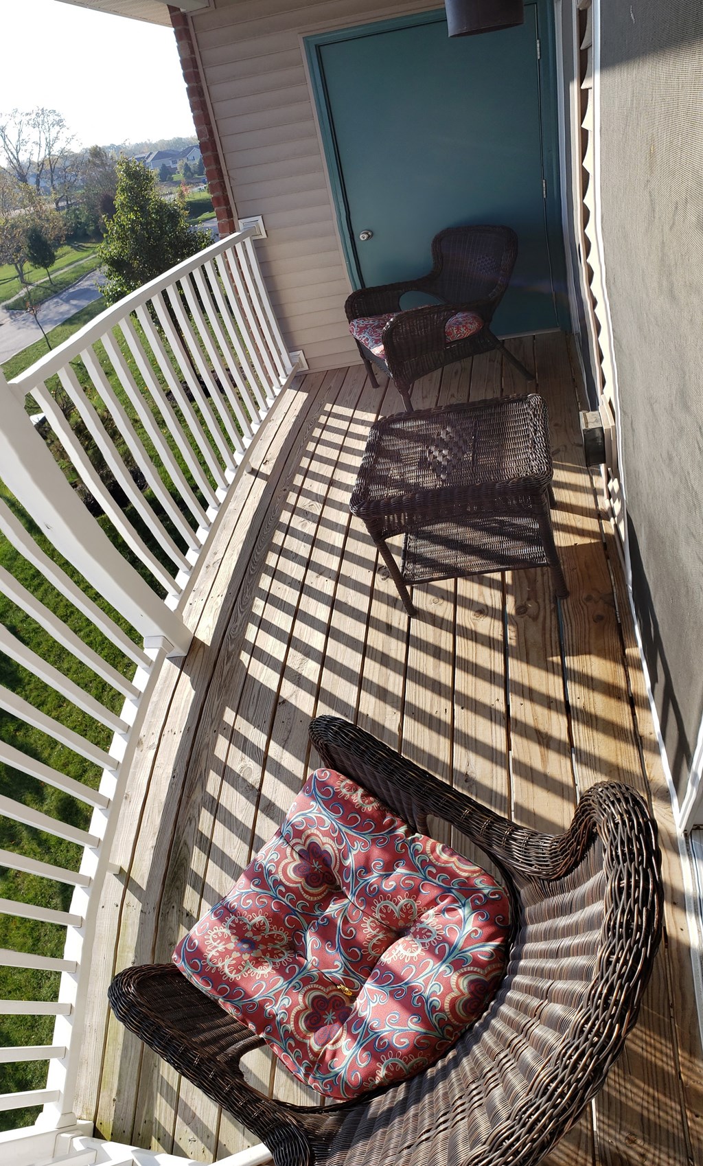 A chair with a floral cushion is on a wooden deck.