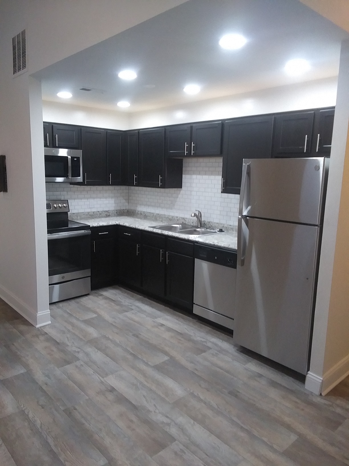 an empty kitchen with black cabinets and stainless steel appliances