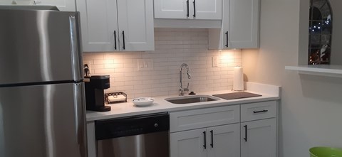 A kitchen with white cabinets and a stainless steel refrigerator.
