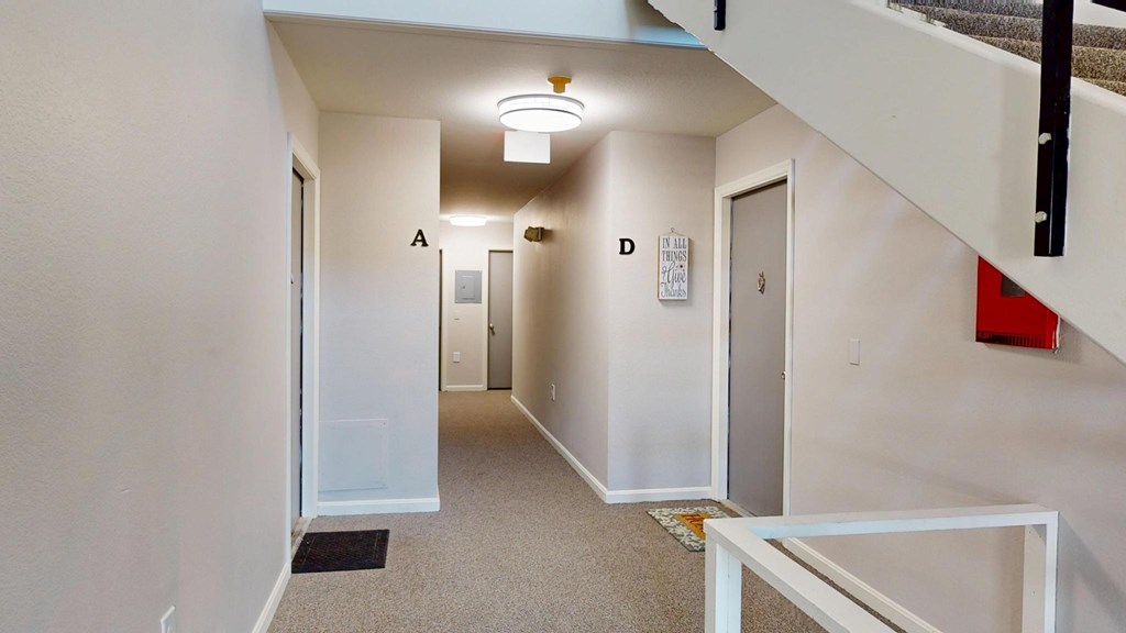 A hallway with a white door on the left and a red object on the right.