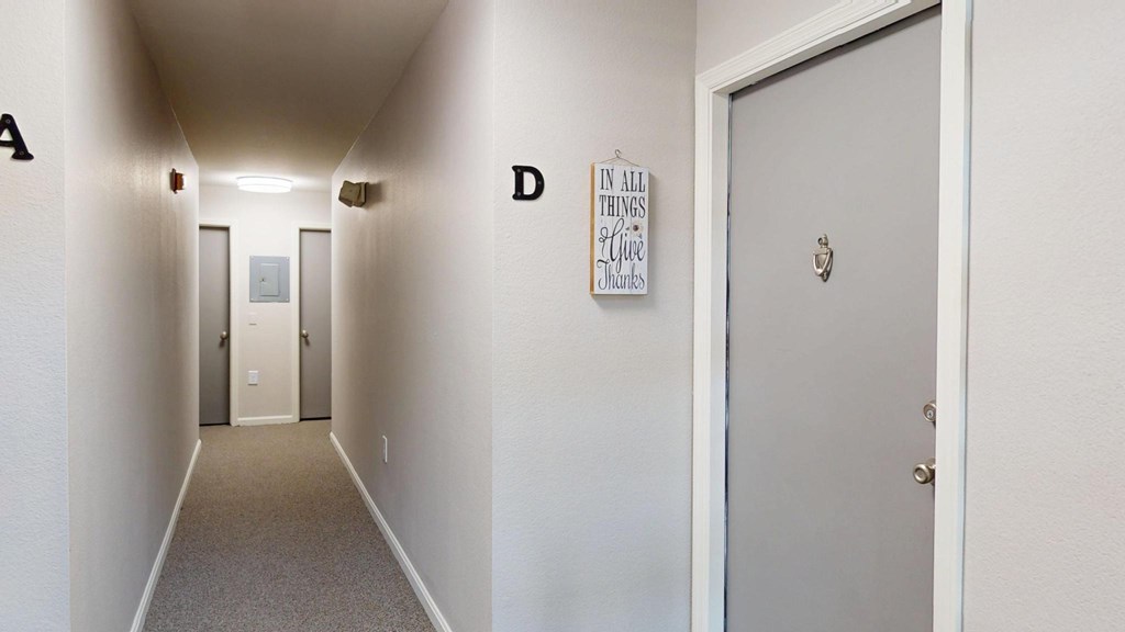 A hallway with doors on the left and right and a poster on the wall.