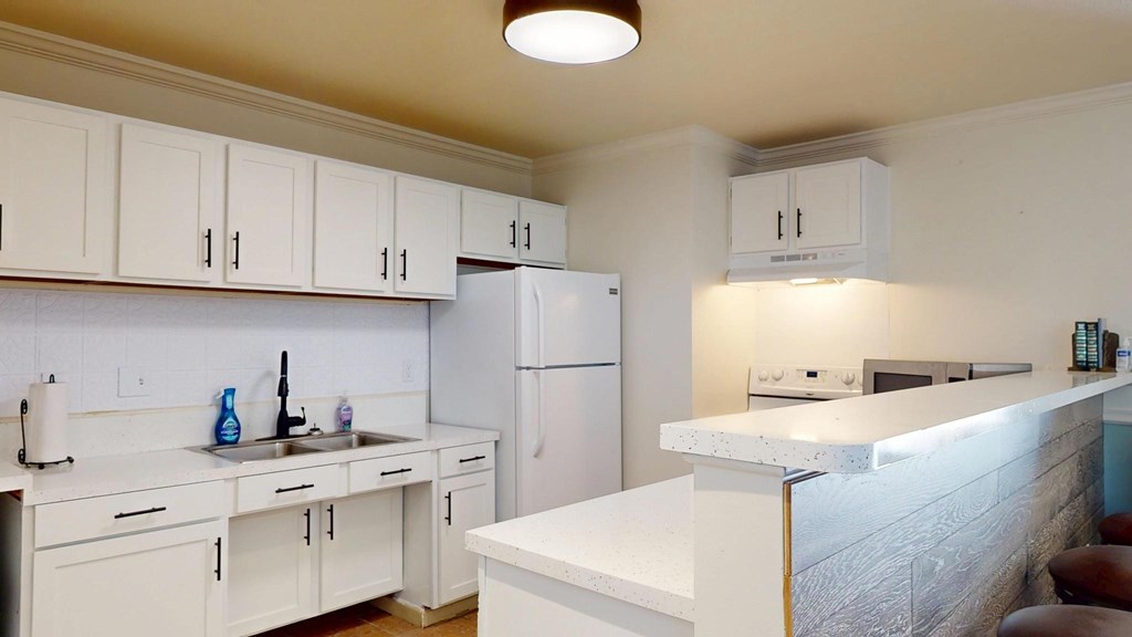 A kitchen with white cabinets and appliances.