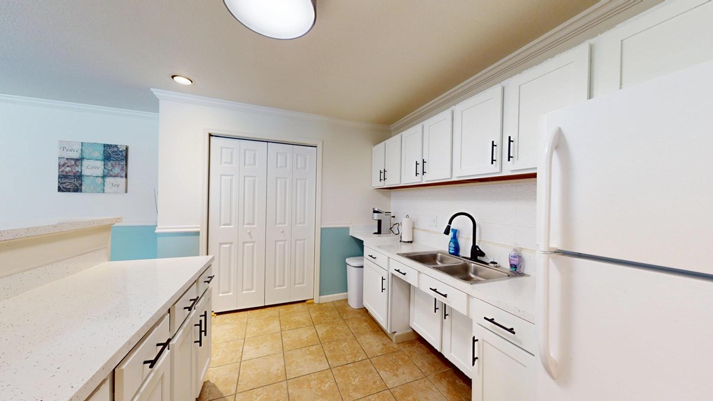 A kitchen with white cabinets and a white fridge.