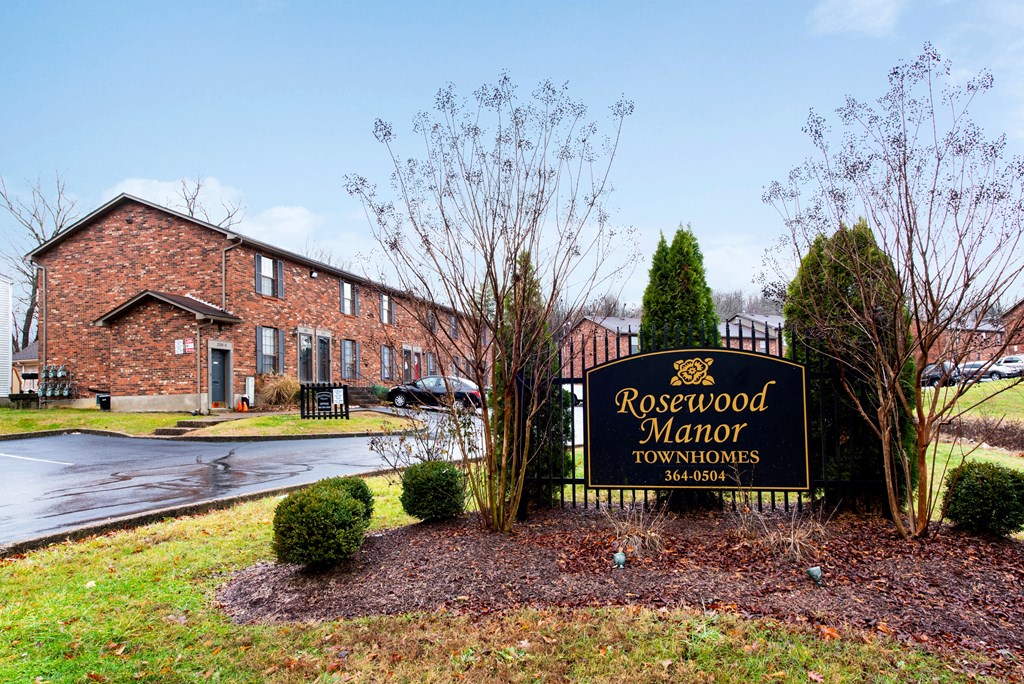 the sign for rosewood manor townhomes in front of a brick building