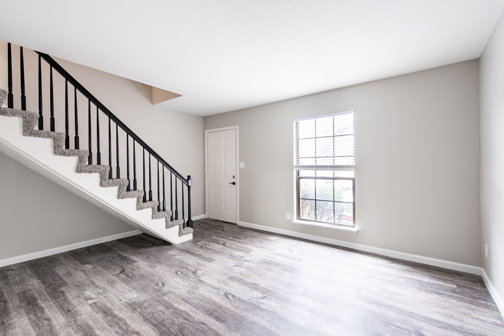 an empty living room with a staircase and a window