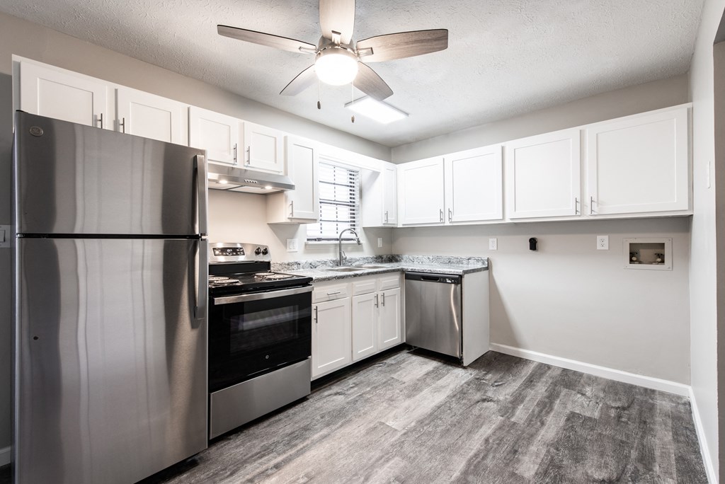 an empty kitchen with stainless steel appliances and white cabinets