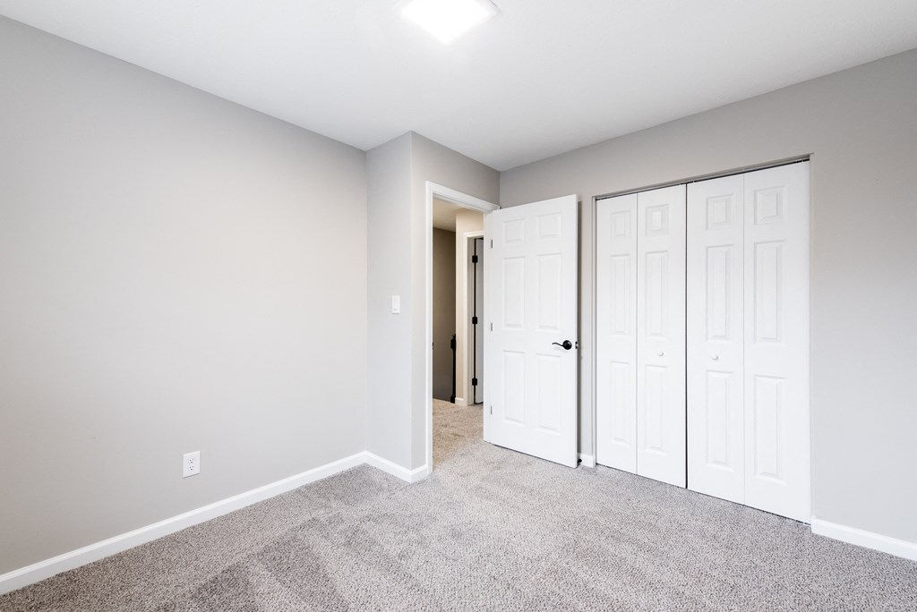 an empty bedroom with two closets and a door to a hallway