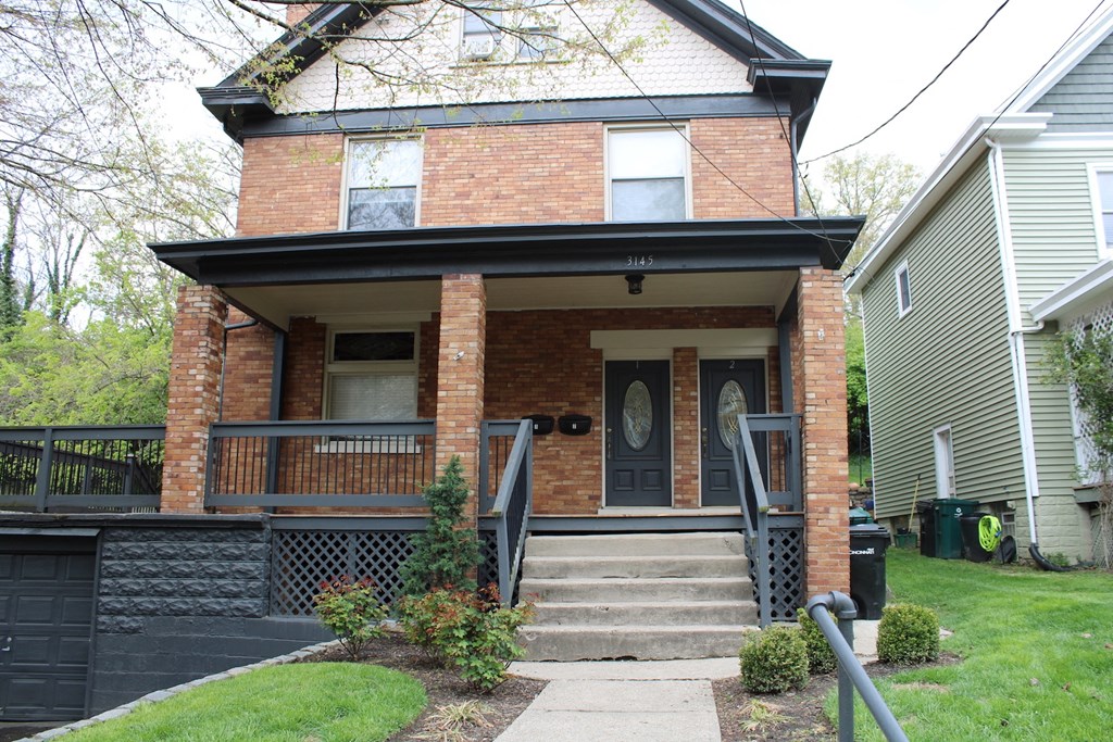 the front of a brick house with a porch and stairs