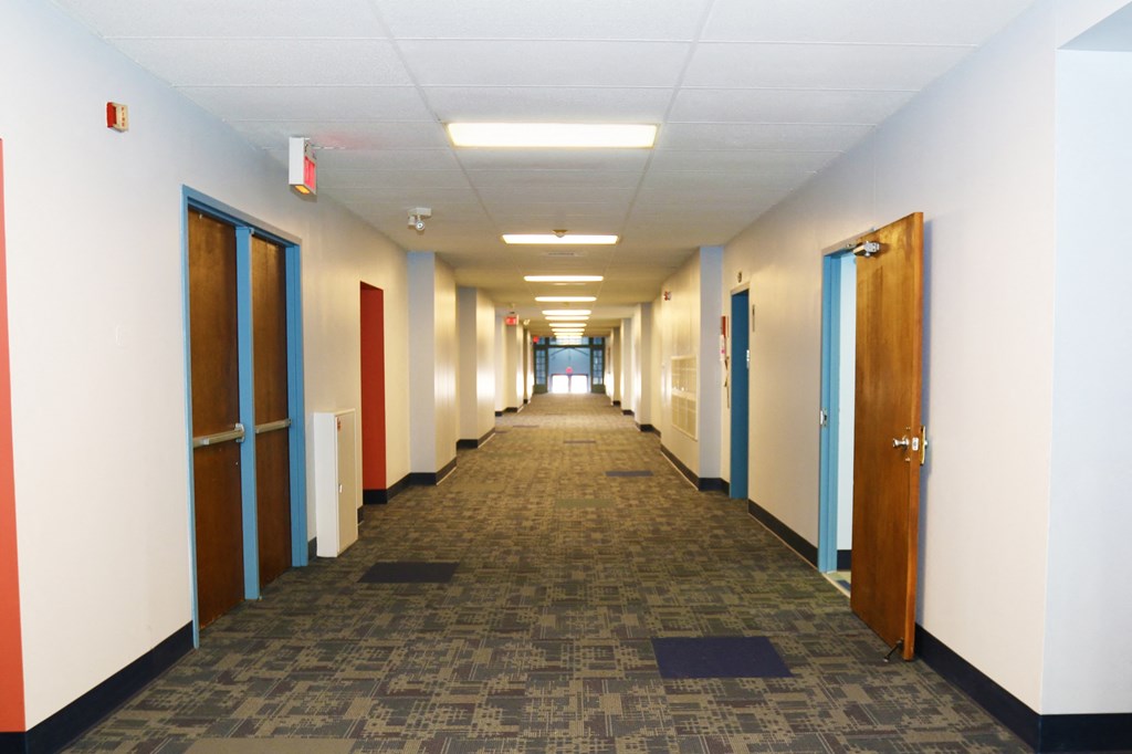 a long hallway with doors and a carpeted floor in an office