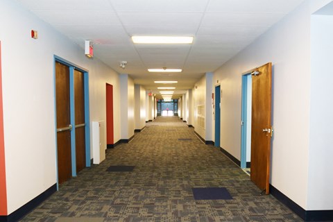 a long hallway with doors and a carpeted floor in an office