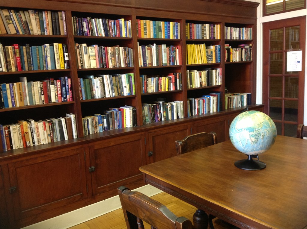 a bookshelf filled with books and a table with a globe
