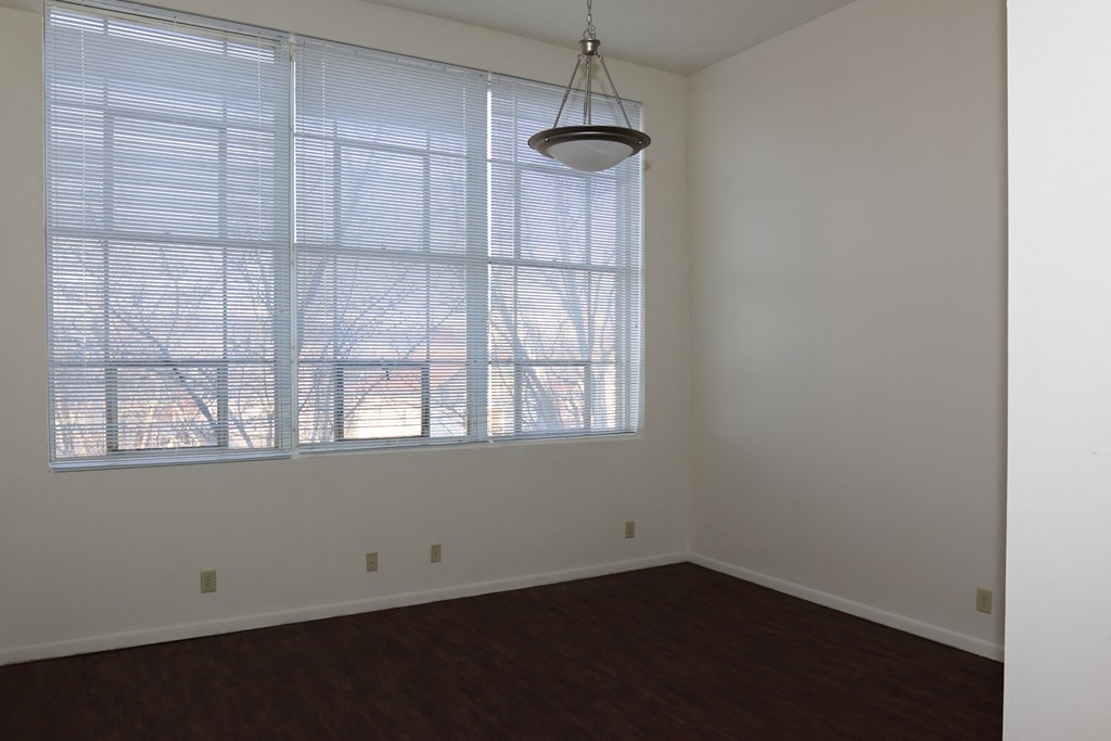 an empty living room with a large window and wooden floors