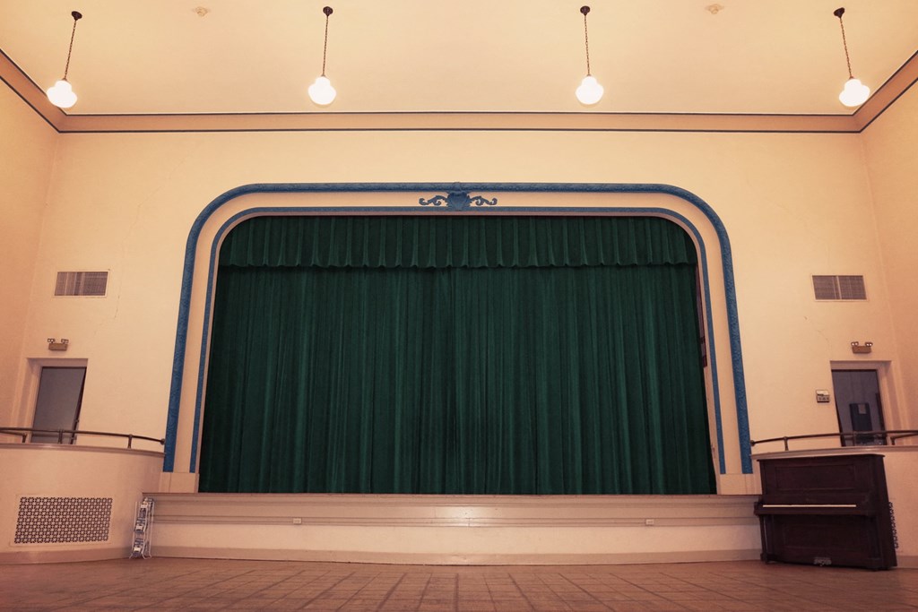 a large green curtain on the stage of an empty auditorium