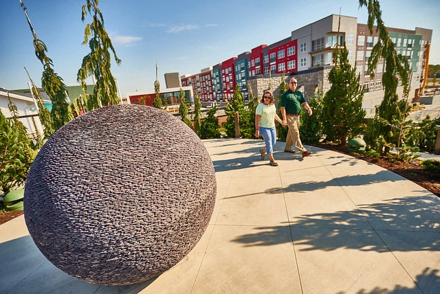 a man and a woman walking past a large sphere sculpture