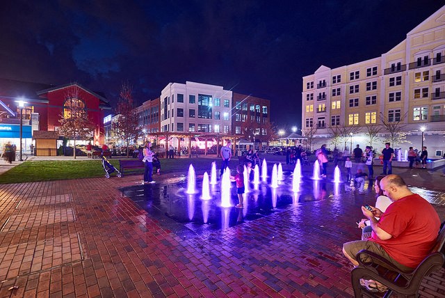 a man sitting on a bench in front of a fountain
