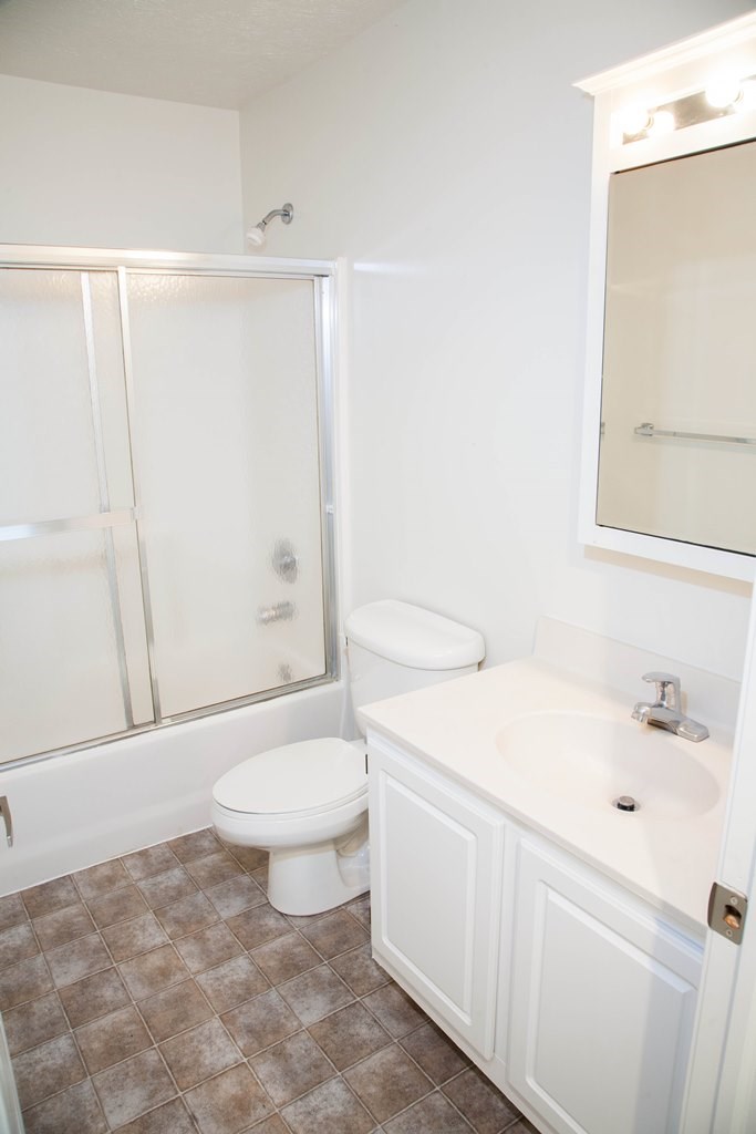 a white bathroom with a shower toilet and sink