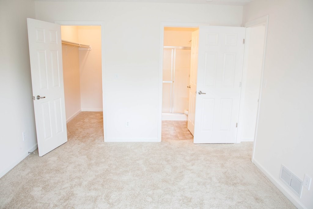 an empty bedroom with three doors and a carpeted floor