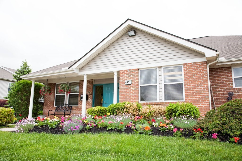 A house with a blue door and a flower bed in front.
