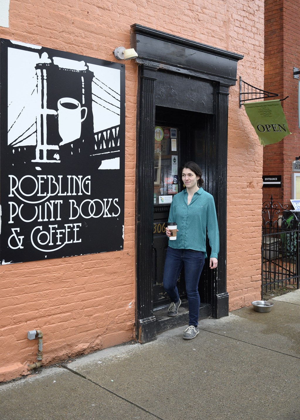 a woman standing in the door of rocking point books and coffee