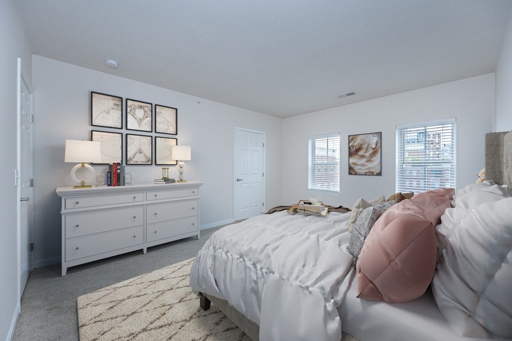 a bedroom with white walls and white furniture and a bed with pink pillows