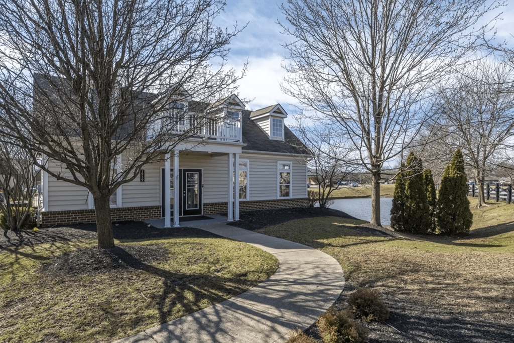 a white house with a driveway and a lake in the background at Traditions at Slate Ridge, Reynoldsburg, OH 43068