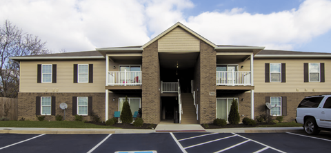 A two-story apartment building with a parking lot in front.