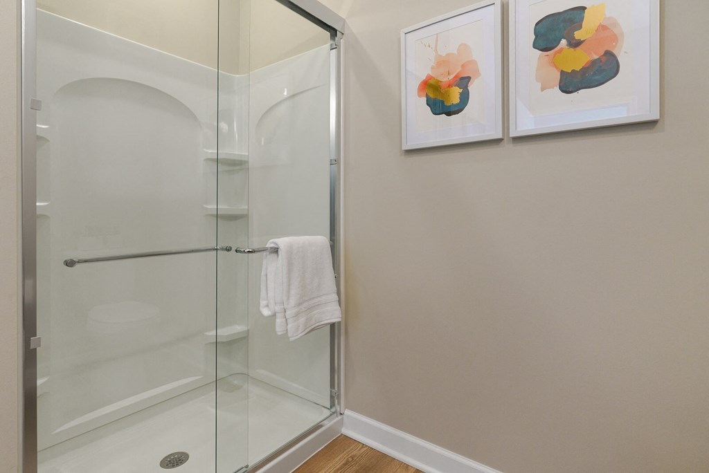 a bathroom with a glass shower and two paintings on the wall at Adelphi Quarter, Columbus