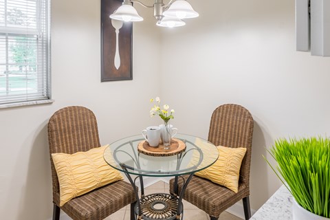 Dining area with a glass table and two wicker chairs at Indian Creek Apartments, Cincinnati