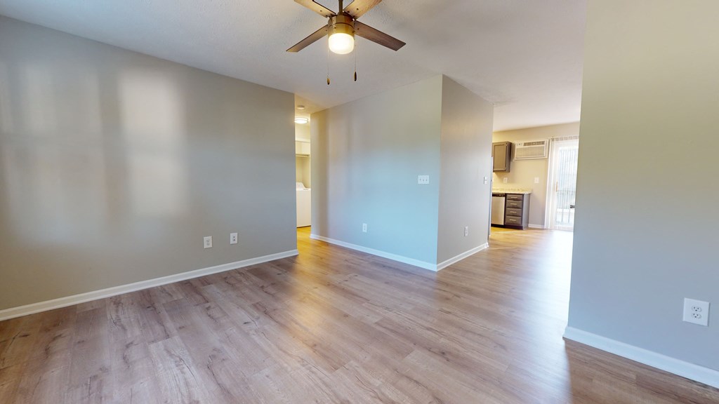 an empty living room with wood floors and a ceiling fan