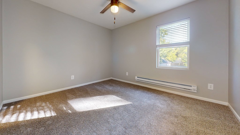 an empty room with a ceiling fan and a window