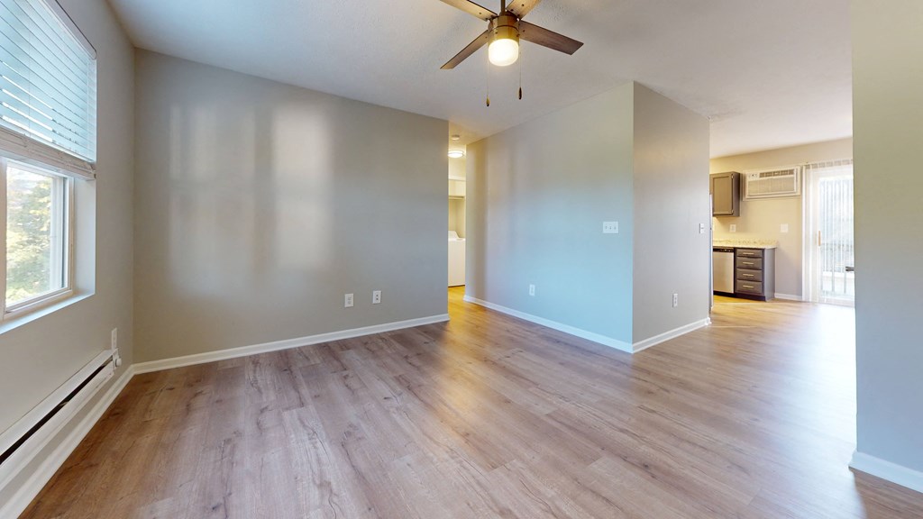 an empty family room with wood floors and a ceiling fan