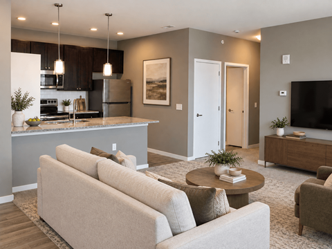 A modern living room with a kitchen area in the background.